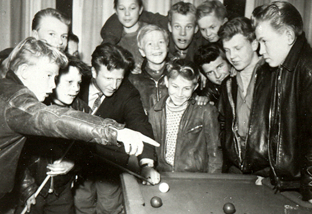 Kerhonohjaaja neuvoo nuoria pelaamaan keilabiljardia Turun Tapulikadun nuorisotilassa 1956.